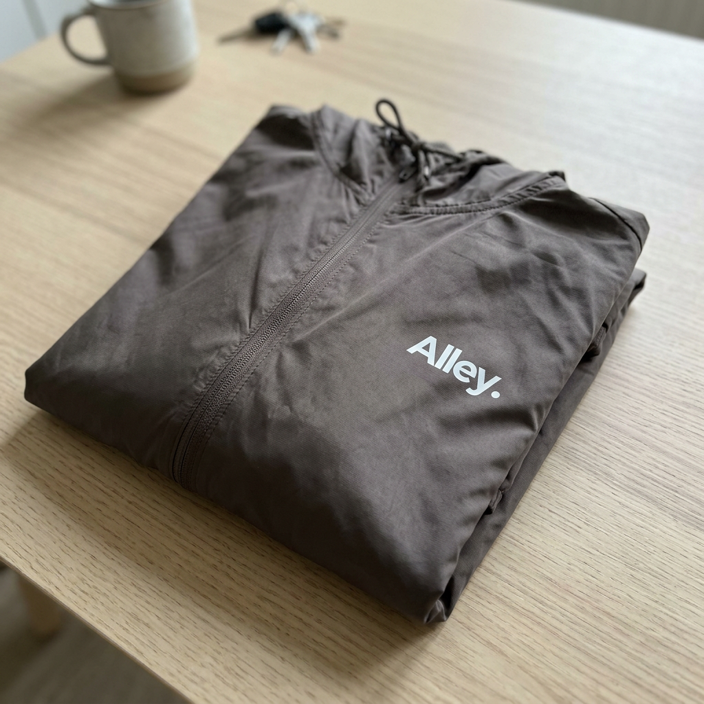 Folded gray hooded windbreaker jacket with Alley logo