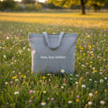 Light grey cotton tote bag with long handles and 'less, but better' front print.