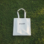 White cotton tote bag with two handles, printed “grounded”