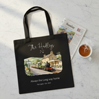 Black canvas tote bag with a printed train and cottage scene, shown with a magazine.