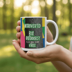 White mug with colorful nature quote held in a hand outdoors