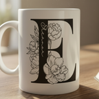 White mug close-up with black letter D and floral line art