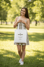White canvas tote bag with graduation print, held by a woman