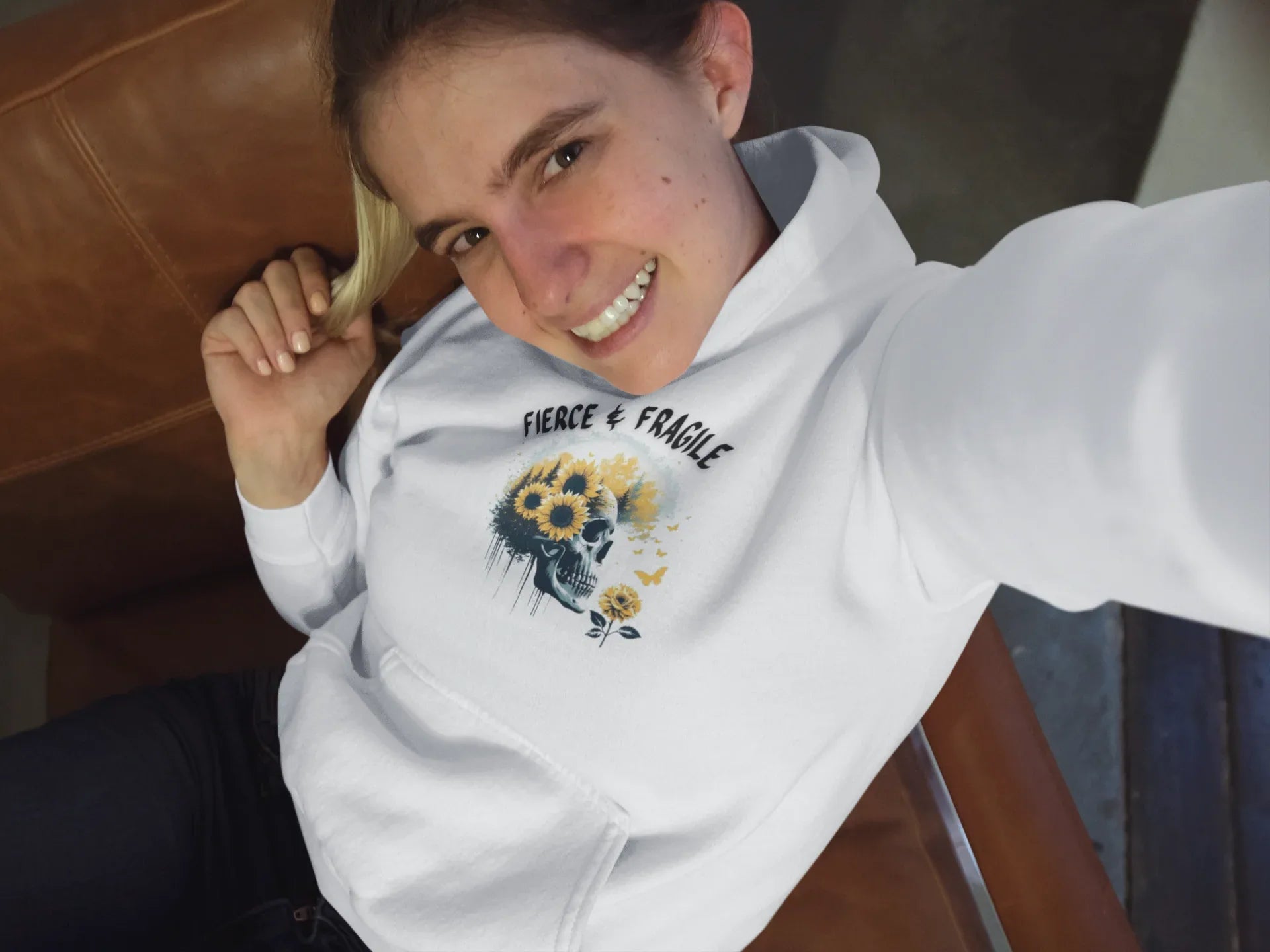 White hooded sweatshirt with front graphic skull and flower design, long sleeves and front pouch pocket.