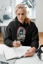 Black unisex hoodie worn by person, featuring front rainbow heart graphic and “I TEACH SWEET LITTLE Hearts”