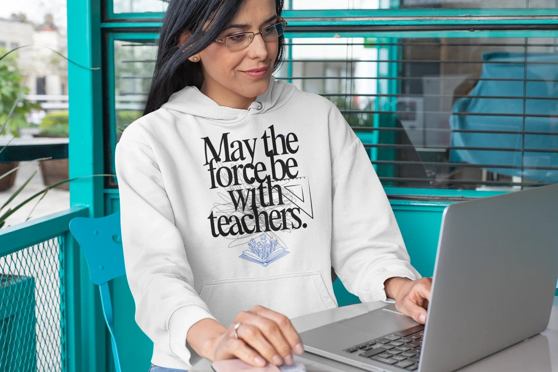 White hooded sweatshirt with front graphic text and blue book emblem, worn indoors.