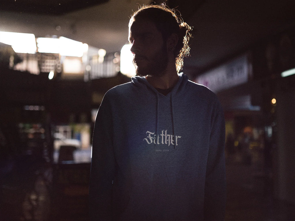 Person wearing a dark navy pullover hoodie with front pocket, hood drawstrings, and logo.
