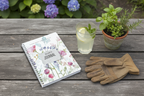 Elsie's personalised Bloom Where You Are Planted A5 floral journal lying on a rustic garden table with lemonade, gardening gloves and a potted herb in a British country garden