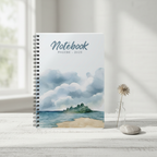 Phoebe's personalised coastal watercolour spiral notebook standing upright on whitewashed wood with a dried beach flower in a glass bottle and a smooth pebble in a premium studio product photo