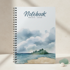 Maisie's personalised coastal watercolour spiral notebook standing upright on a pale cream stone surface with sea glass and a small white shell in a premium studio product photo