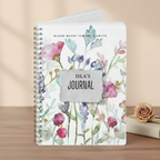 Isla's personalised Bloom Where You Are Planted A5 floral journal standing upright on a warm studio surface with a dried rose in a premium studio product photo