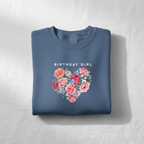 Blue crewneck sweatshirt with “Birthday Girl” text and a floral heart graphic on chest
