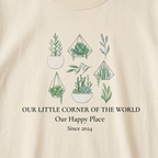 Natural t-shirt close-up with green botanical graphic and “Our Happy Place,” “Since 2024”