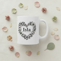 White ceramic mug with floral heart wreath and “Isla” on front