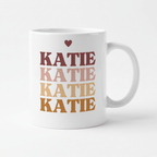 Personalised white mug with large stacked “KATIE” text and a small heart above.