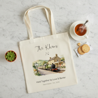 White canvas tote bag with printed train and cottage scene on the front.