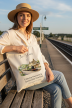 White canvas tote bag held by a person, with a printed scenic train illustration.