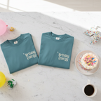 Two crew-neck T-shirts: teal and light teal, both with Birthday Energy+ graphic