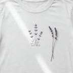 Close-up of white t-shirt: lavender sprig embroidery with custom name and year