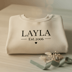 Cream crewneck sweatshirt with LAYLA and Est.2006 graphic, front view