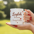 White ceramic mug in hand with red 'Laylah' and date '10th July 2024' hearts.