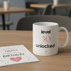 White ceramic mug on table with "level 30 unlocked" text and small heart