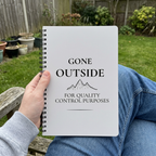 Light grey Gone Outside notebook held on a garden bench