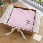 Light-pink Mountains Are Calling sweatshirt gift-wrapped in an open box