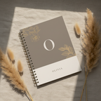 A5 notebook with taupe cover, gold monogram O, floral branch design, and spiral binding.