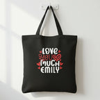 Black tote bag with printed hearts and text: “LOVE YOU MUCH EMILY”