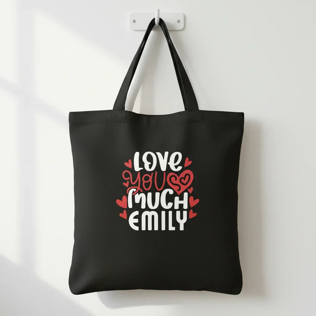 Black tote bag with printed hearts and text: “LOVE YOU MUCH EMILY”
