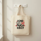 White tote bag with 'LOVE YOU MUCH EMILY' heart text print.