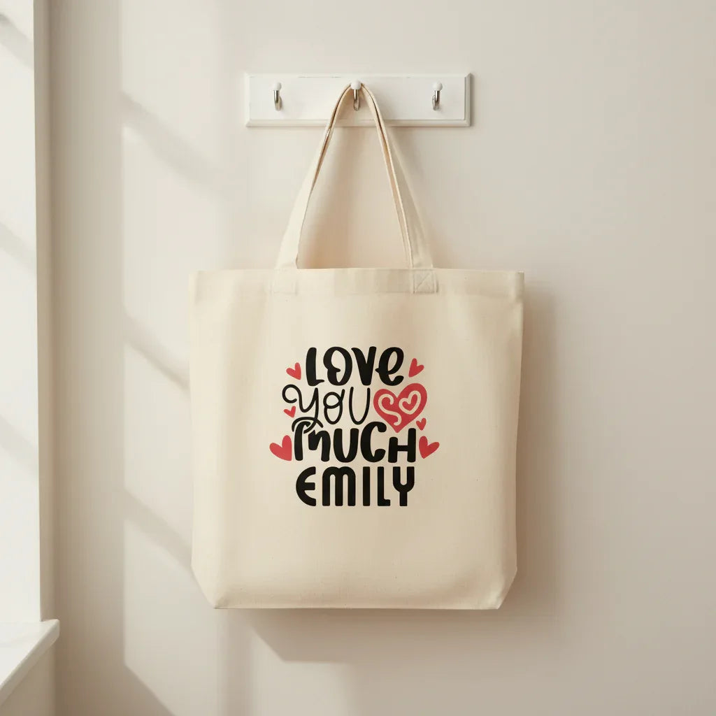 White tote bag with 'LOVE YOU MUCH EMILY' heart text print.
