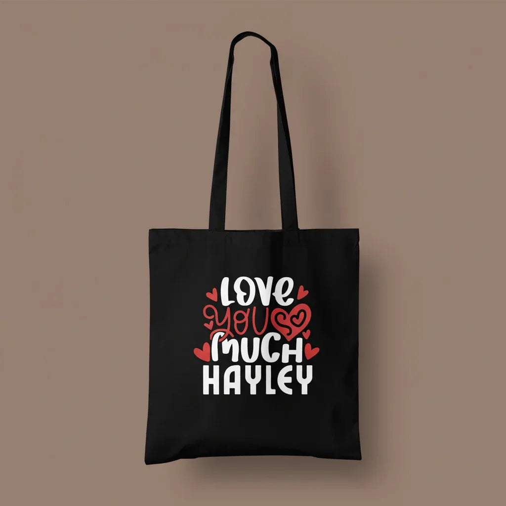 Black tote bag with printed hearts and text: “LOVE YOU MUCH HAYLEY”