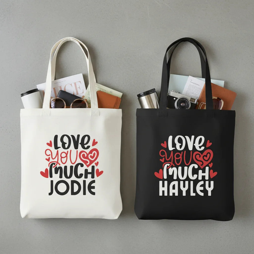 Two tote bags, one white and one black, each with printed hearts and name text