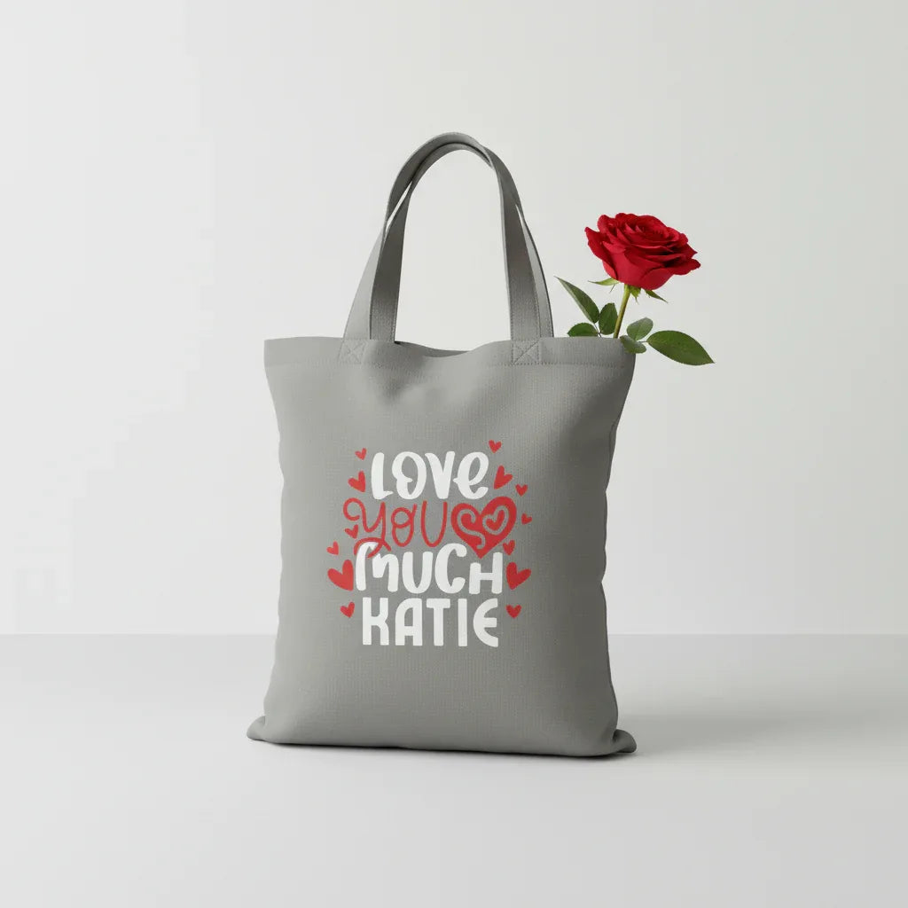 Gray tote bag with 'LOVE YOU MUCH KATIE' heart text print.