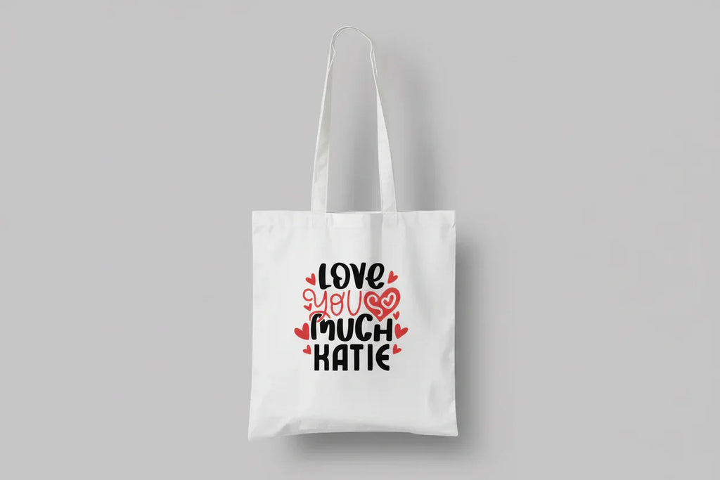 White tote bag with printed hearts and text: “LOVE YOU MUCH KATIE”