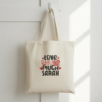 White tote bag with 'LOVE YOU MUCH EMILY' heart text print.