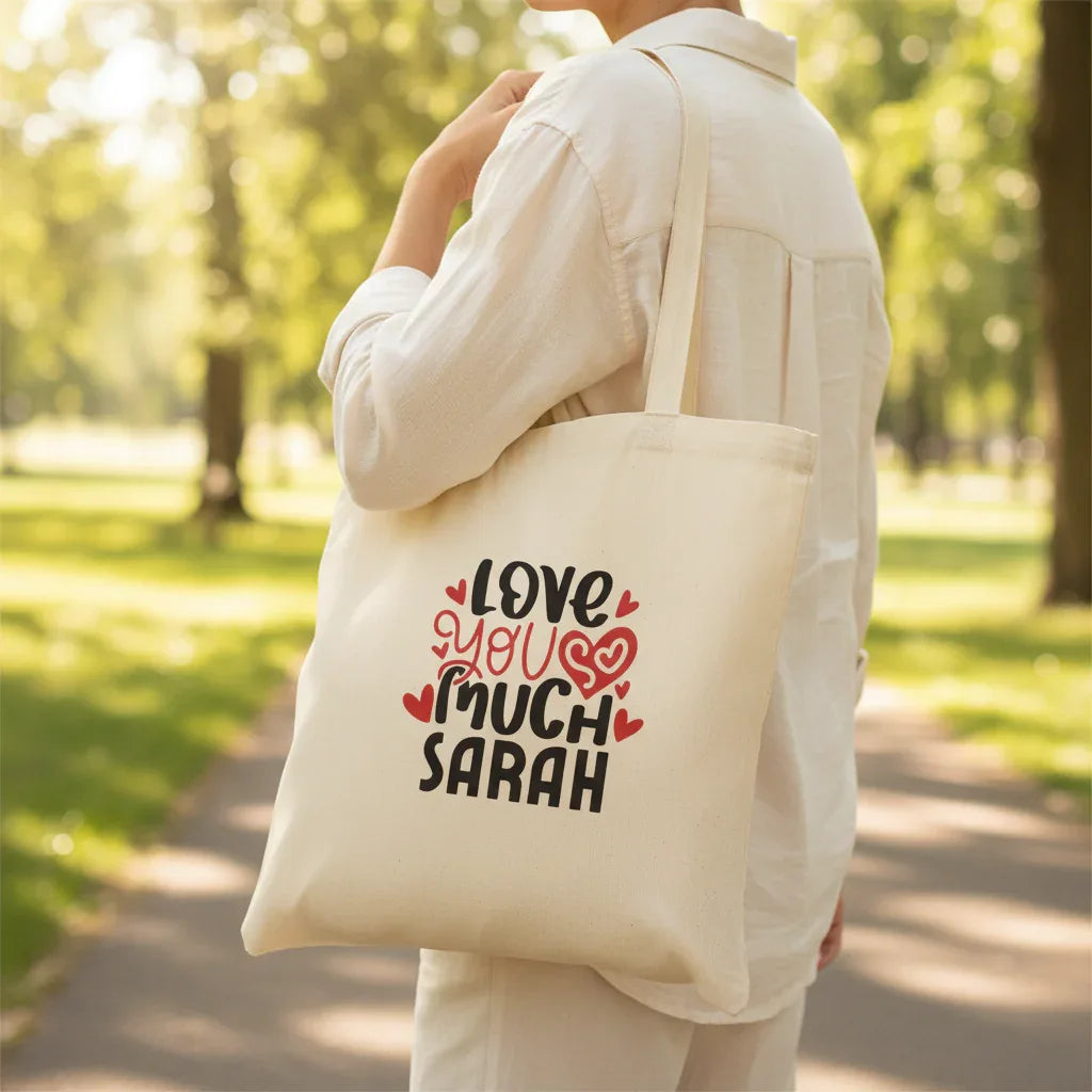 White tote bag with 'LOVE YOU MUCH SARAH' heart text print.
