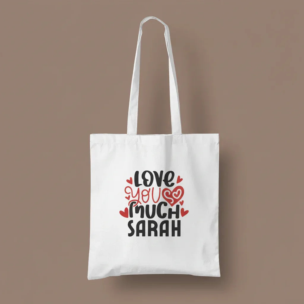 White tote bag with printed hearts and text: “LOVE YOU MUCH SARAH”