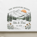 White T-shirt with mountain landscape graphic, floral border, and custom names