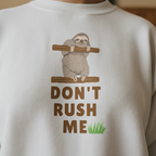 White sloth graphic sweatshirt close-up with “DON’T RUSH ME” text and green grass