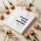 White T-shirt folded with 'I have two names' print and small heart detail at center.