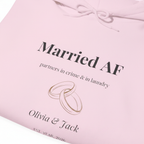 Light pink hoodie with “Married AF” print, partners line, ring graphic