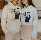 White and light-blue couple graphic hoodies worn together, front prints and hood.
