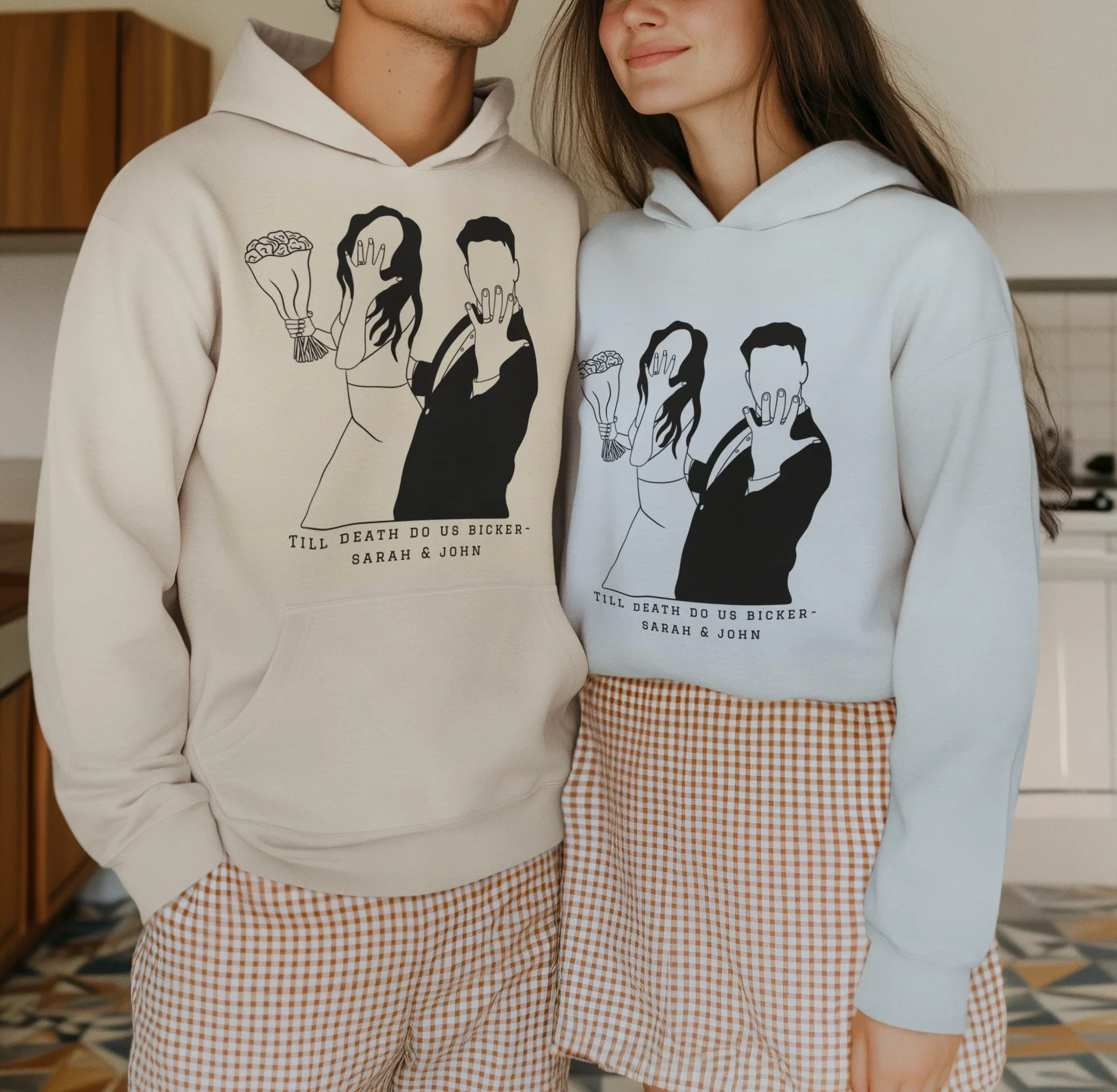 White and light-blue couple graphic hoodies worn together, front prints and hood.