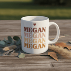 White ceramic mug with heart above stacked MEGAN text, single side view