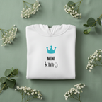 White hooded sweatshirt with teal crown logo and “MINI KING” front print