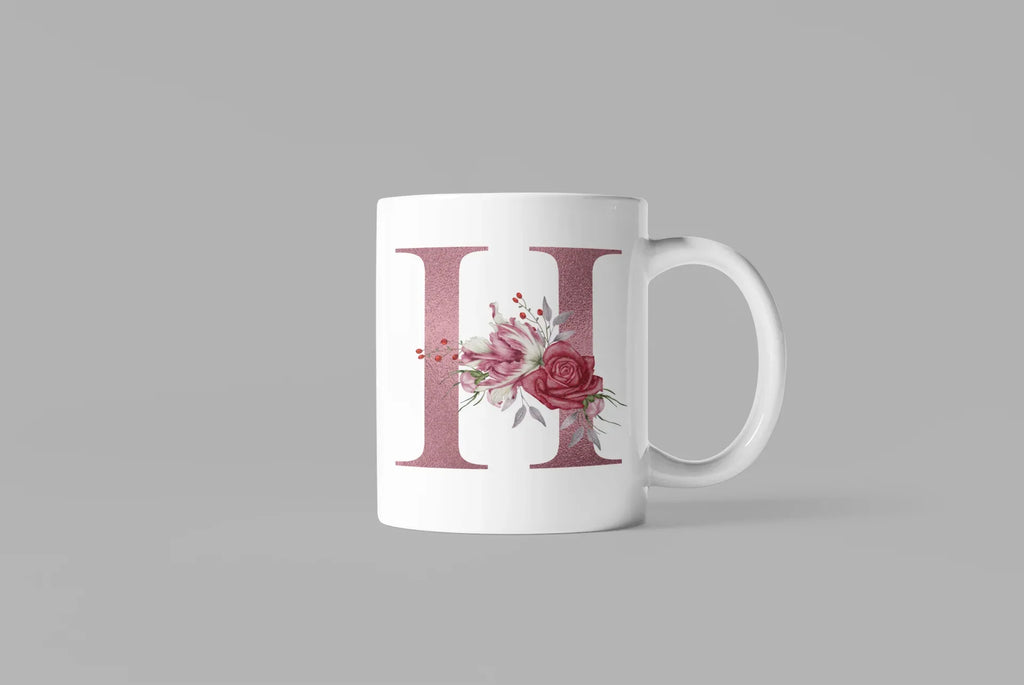 White ceramic mug with floral letter H design on front, side handle and base visible