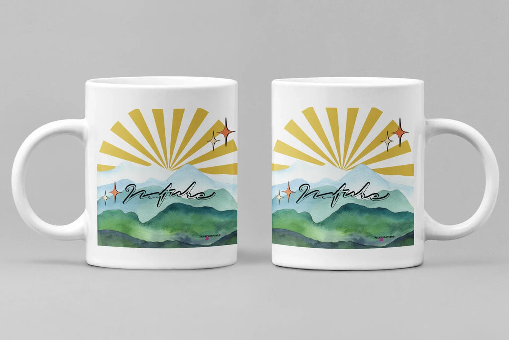 White coffee mug with sunrise rays and mountain landscape graphic on front